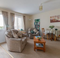 A living room with two armchairs a wooden coffee table and a small dining table with three chairs at Little Barn Cucklington near Wincanton