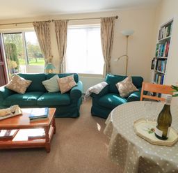 A living room with a sofa, table, and bookshelf at Little Barn in Cucklington near Wincanton