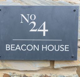 A house number plaque reading No 24 Beacon House mounted on a stone wall at Beacon House in St Agnes
