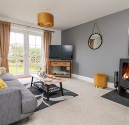 A living room with a gray sofa yellow pillows coffee table and fireplace at Beacon House in St Agnes
