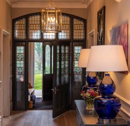 An entryway with stained glass doors a console table with blue lamps and flowers at Oakdene Country House Sedbergh