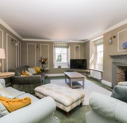 A living room with sofas pillows a coffee table a television and a fireplace at Culdrose Manor in Helston