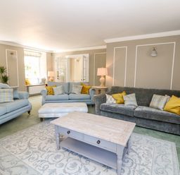 A living room with sofas cushions a coffee table and lamps at Culdrose Manor in Helston