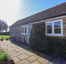 A house entrance with stone path and plants at Cartwheel Cottage in Yearsley