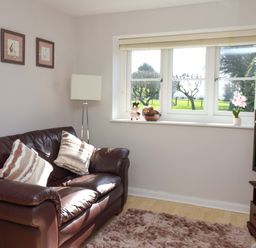 A living room with a sofa and window at Cartwheel Cottage in Yearsley