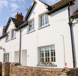 A row of white terraced houses with tiled roofs and stone wall at 3 Elm Cottage in Carhampton
