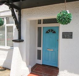 Front entrance with a blue door and hanging green decorations at The White Cottage in Weymouth