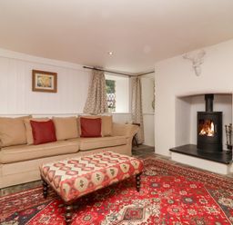 A living room with a sofa and fireplace at Old Maids Cottage in Woolacombe