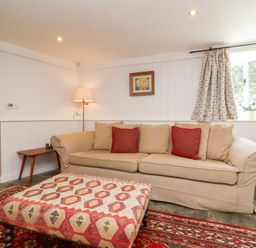 A living room with a sofa and ottoman at Old Maids Cottage Woolacombe
