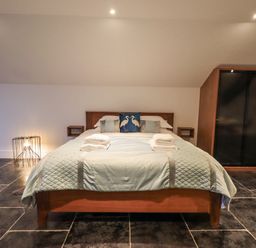 A bedroom with a double bed folded towels on the bed and a wardrobe at The Boat House at Louper Weir in Bowness-On-Windermere