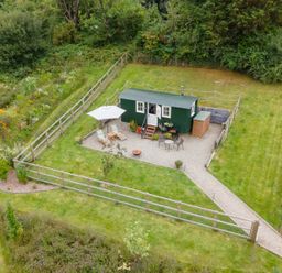 A green cabin with seating and an umbrella at Onnen in Oakford near Aberaeron