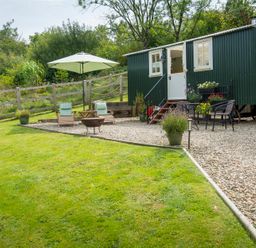 An outdoor area with a green shed and seating at Onnen Oakford near Aberaeron