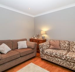 A living room with two sofas a wooden chest of drawers and a table lamp at 10 Pen Llanw Tides Reach in Rhosneigr