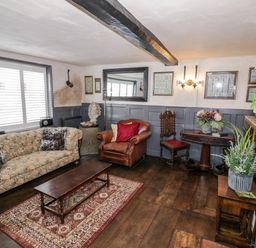 A living room with a sofa armchair wooden coffee table and decorative plants at The Old Paper Shop in Tewkesbury