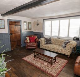 A sitting room with two leather armchairs a patterned sofa coffee table and a rug at The Old Paper Shop in Tewkesbury