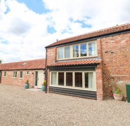 A brick and timber house with multiple windows and a gravel driveway at Cobblers Barn in Repps With Bastwick near Potter Heigham