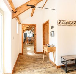 A hallway with wooden floor beams a small wooden table and wall hooks at Cobblers Barn in Repps With Bastwick near Potter Heigham