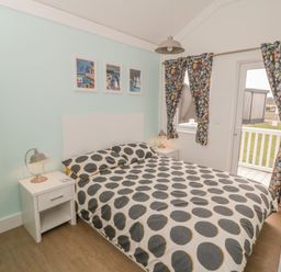 A bedroom with a double bed bedside tables lamps and curtains with a pebbled pattern at Shore Thing 280 in Wilsthorpe