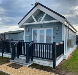 A small blue cabin with white trim and black railing on a porch at Shore Thing 279 in Wilsthorpe