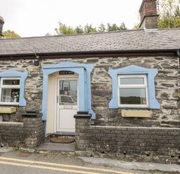 Front of a stone cottage with two windows and a door framed in blue at Crud yr Awel in Braichmelyn near Bethesda