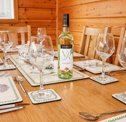 A dining table set with wine glasses plates utensils and a bottle of white wine at Watersview Lodge in Rudyard near Leek