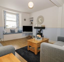 A living room with grey sofas a wooden coffee table a TV and a window seat at Potter Hill Cottage in Pickering