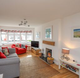 A living room with a grey sofa a red armchair a television and a fireplace at Sisial-Y-Mor in Rhosneigr