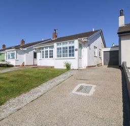 A bungalow with a driveway and front lawn along with neighboring houses at Sisial-Y-Mor in Rhosneigr