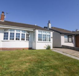 A single-story house with a front lawn and large windows at Sisial-Y-Mor in Rhosneigr