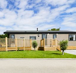 A single-story house with a wooden ramp and steps surrounded by grass at Pinehurst Lodge in St Day