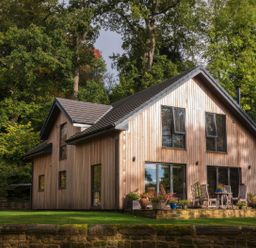 A house with wooden siding and patio furniture at Romsey Lodge in Wark