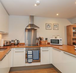 A kitchen with wooden countertops white cabinets stainless steel oven toaster microwave and wooden display cabinet at 42 Dart Marina in Dartmouth