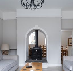 A living room with two grey sofas a wooden coffee table and a black stove in an arched wall at Keepers Cottage in Hawkshead