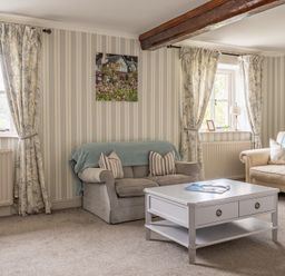 A living room with two sofas a coffee table and two windows with curtains at Grassholme in Hawkshead