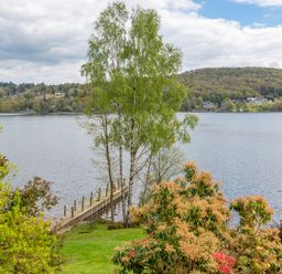 A lake with a wooden jetty and trees in the foreground at Grassholme in Hawkshead