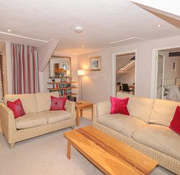 A living room with two beige sofas red pillows wooden coffee table and bookshelf at Manor Studio in Dartmouth