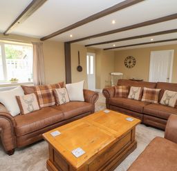 A living room with brown sofas and a wooden coffee table at Crag View in West Woodburn