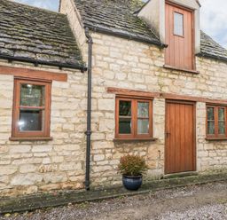 Stone cottage exterior with wooden windows a wooden door and two potted plants at Chapel Cottage in Leonard Stanley near Kings Stanley