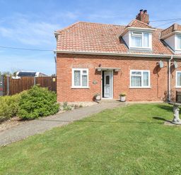 A brick house with a tiled roof and front garden with grass and bushes at Lillies Pad in Methwold near Feltwell