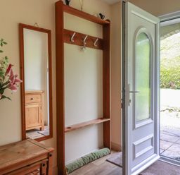 A hallway with a coat rack and mirror at Underlanes in Boscastle
