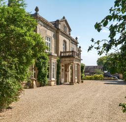 A house with a balcony and gravel driveway at Milton Manor in Milton On Stour