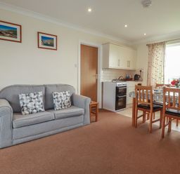A living room with a sofa and dining area at Little Lanes in Boscastle