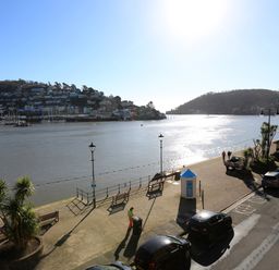 A riverside promenade with benches street lamps and parked cars beside a body of water at 2 Embankment House in Dartmouth