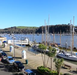 A marina with boats docked along the waterfront and cars parked on the street at 2 Embankment House in Dartmouth