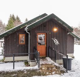A wooden cabin with a ramp entrance and snow on the ground at Torbreck Chalet in Kincraig