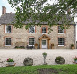 A stone house with a gravel driveway and flower pots at Shifford Manor Farm in Shifford near Bampton Oxfordshire