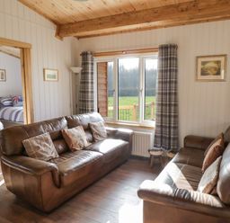 A living room with two brown leather sofas and plaid curtains at Top Style Orchard in Hallow