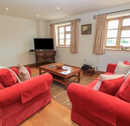 A living room with a sofa and television at Bramble Cottage in Babcary near Lydford-On-Fosse