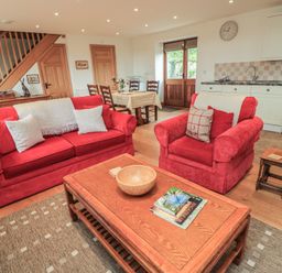 A living room with red furniture and a dining area at Bramble Cottage in Babcary near Lydford-On-Fosse