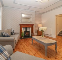A living room with sofas and a coffee table by a fireplace and stairs in the background at Greenlawns in Burnham-On-Sea